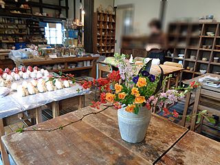 いけばな作品・ボケ、ブラックリーフ、ピンク ラースクパー（千鳥草）、紫アスター、スプレーバラ(オレンジ）